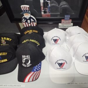 Military and veterans' hats for sale, including black hats with insignia and white hats for the Veterans Memorial Mission. Pricing displayed.