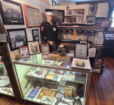 Nautical memorabilia display featuring a historical naval uniform, photographs, awards, and artifacts, highlighting maritime heritage.